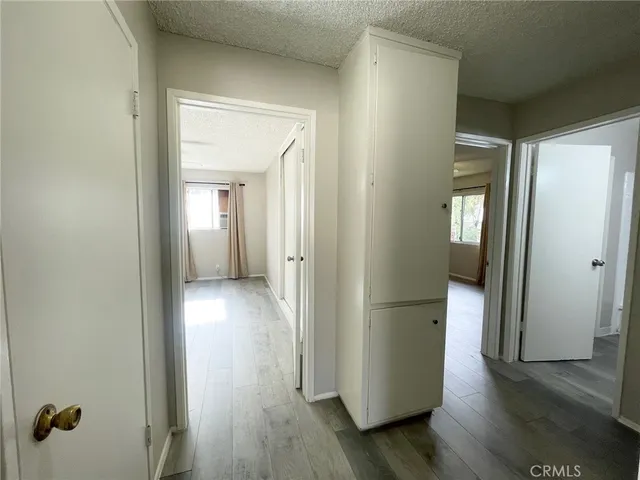 a view of a hallway with wooden floor and a cabinet