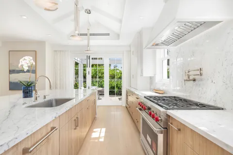 a kitchen with stainless steel appliances kitchen island granite countertop a sink and a white wooden cabinets