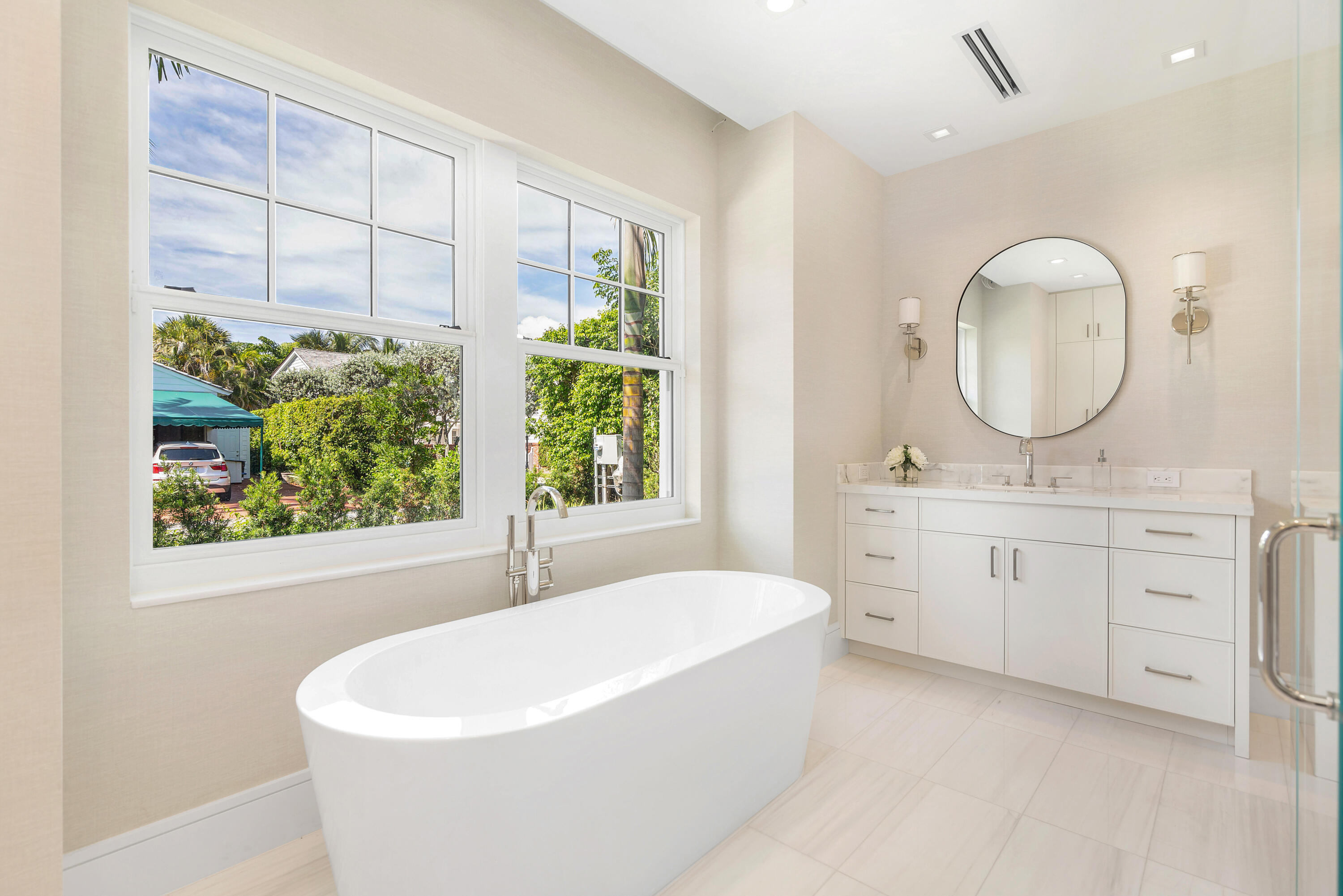 223 Monterey Road Palm Beach, FL 33480 - Photo 26 of 45 a bathroom with a double vanity sink a mirror and a bathtub next to a window