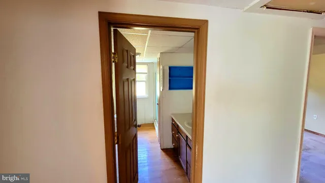 a view of a hallway with wooden floor and a bathroom