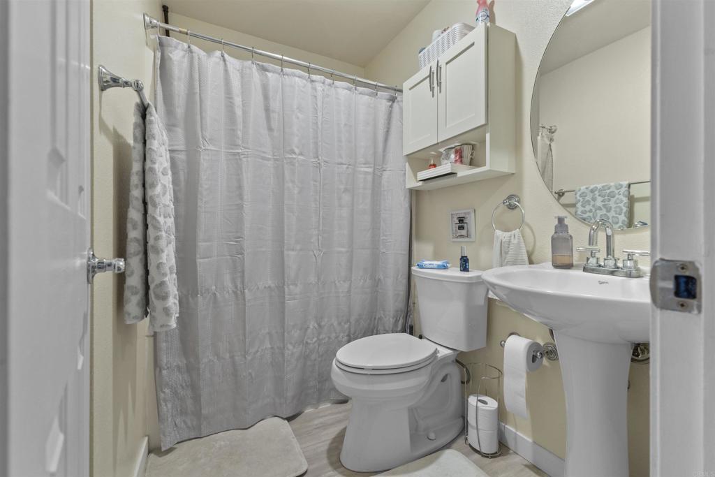 495 San Pasqual Valley Road, Unit 144 Escondido, CA 92025 - Photo 6 of 20 a bathroom with a sink a toilet and shower curtain