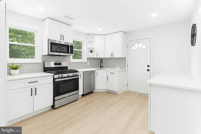 a kitchen with white cabinets stainless steel appliances and a window