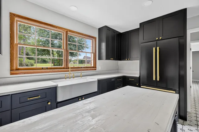 a kitchen with stainless steel appliances kitchen island granite countertop a refrigerator a sink and wooden cabinets