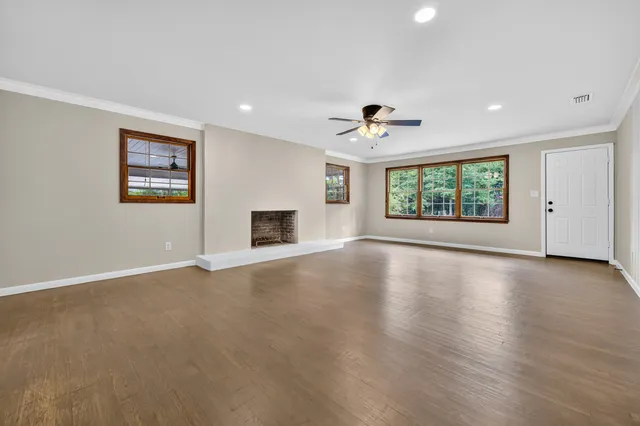 a view of an empty room with a window and wooden floor