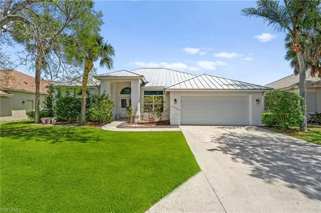 a front view of a house with a garden and trees