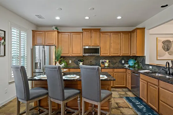 a kitchen with a dining table chairs stainless steel appliances and cabinets