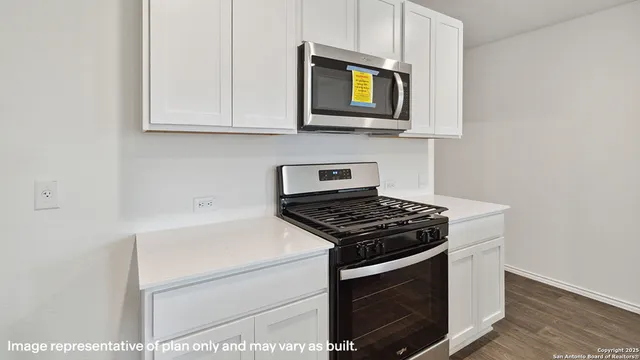a kitchen with stainless steel appliances granite countertop white cabinets a stove top oven