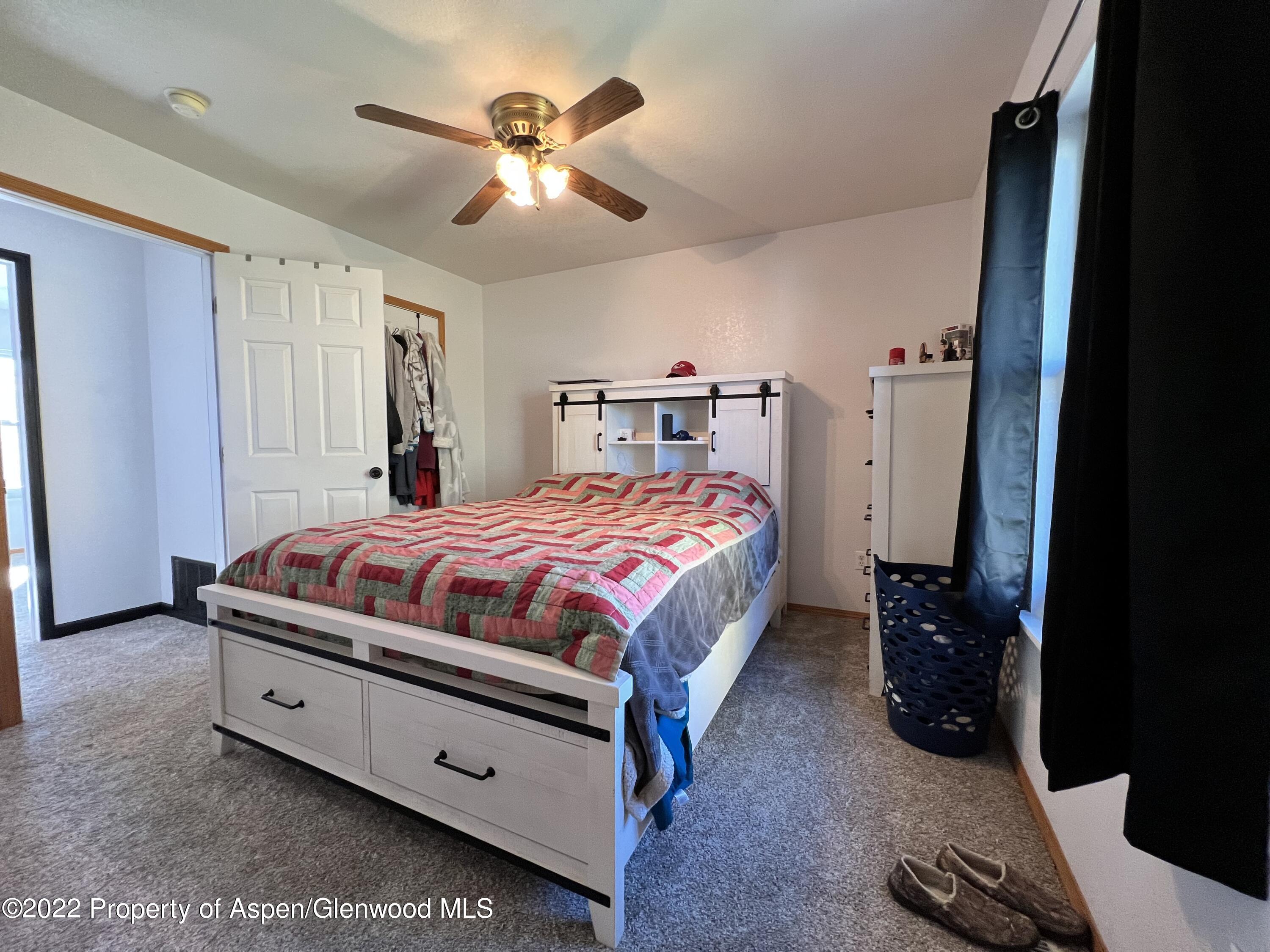 2447 Meadow Circle Rifle, CO 81650 - Photo 15 of 36 a bedroom with a large bed and a chandelier