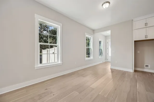 an empty room with wooden floor and windows