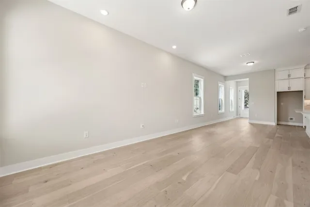 a view of a big room with wooden floor and windows