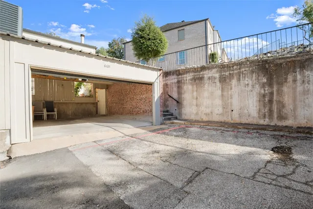 a view of a white house in front of a yard with potted plants