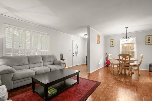 a dining room with wooden floor a chandelier a glass table and chairs