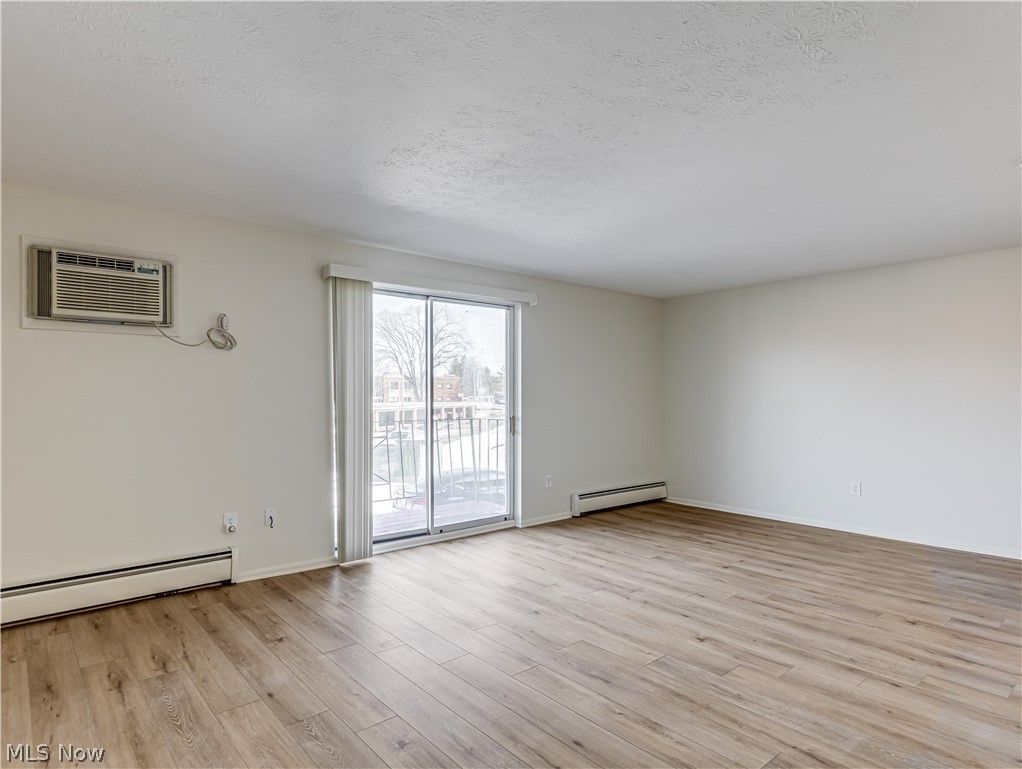 5382 Lee Road, Unit 204 Maple Heights, OH 44137 - Photo 6 of 15 Unfurnished room featuring baseboard heating, light wood-type flooring, and a textured ceiling