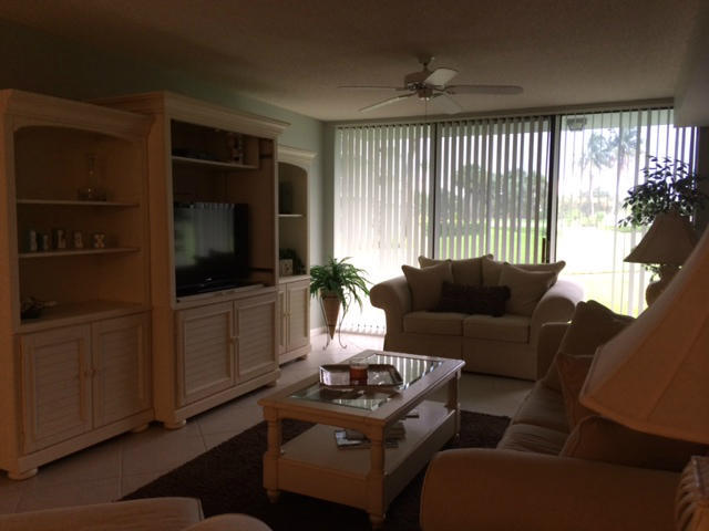 2461 Village Boulevard, Unit 101 West Palm Beach, FL 33409 - Photo 5 of 10 a living room with furniture a flat screen tv and a large window