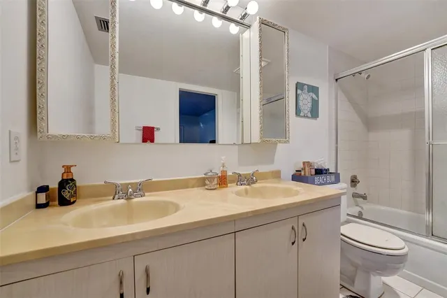 a bathroom with a sink a toilet a mirror and shower