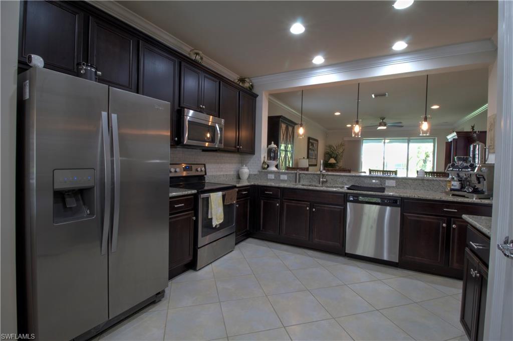 8472 Benelli Court Naples, FL 34114 - Photo 9 of 45 a large kitchen with stainless steel appliances and a refrigerator