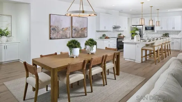 a kitchen with stainless steel appliances a dining table chairs stove and white cabinets