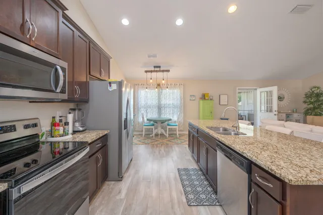 a kitchen with granite countertop lots of counter top space a sink and stainless steel appliances