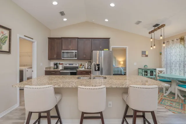 a kitchen with stainless steel appliances granite countertop a table chairs refrigerator and sink
