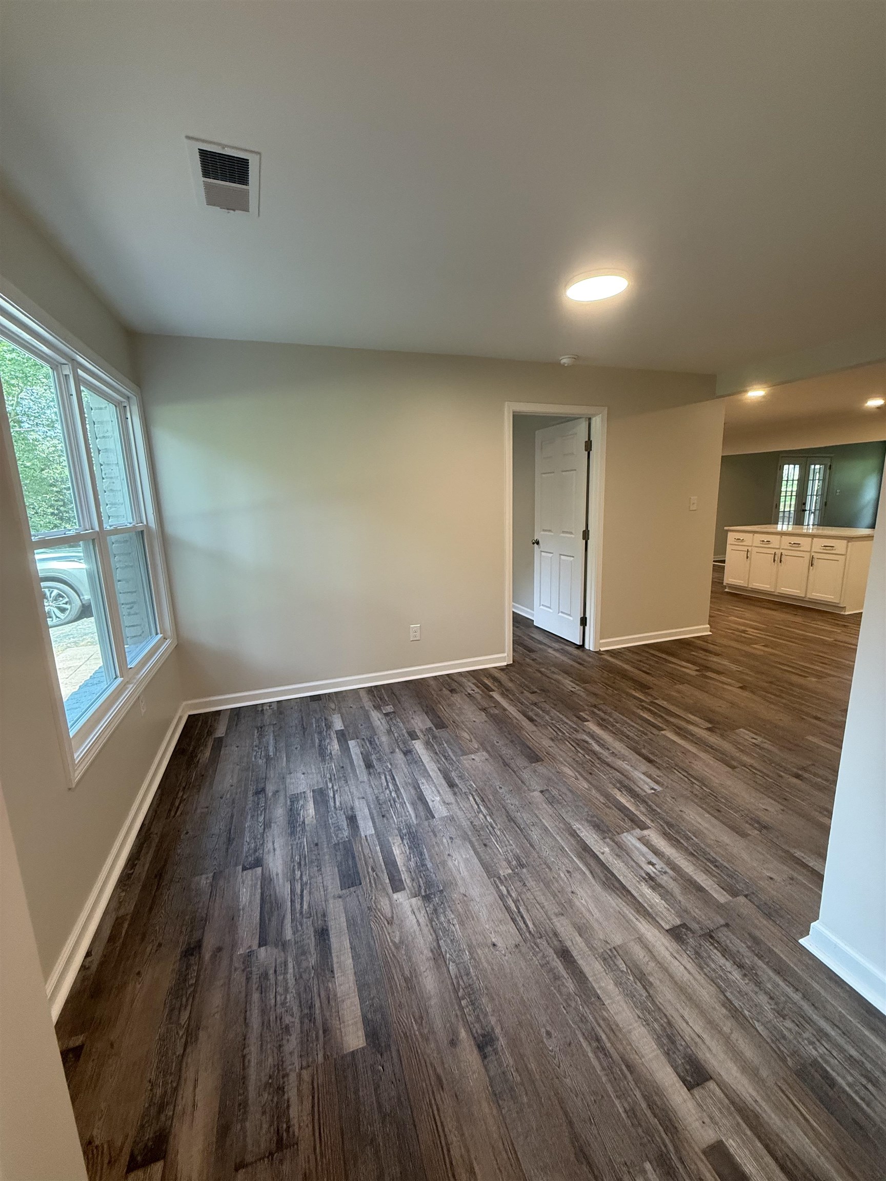 Interior space featuring wood-finish flooring, light neutral wall paint, and white baseboards