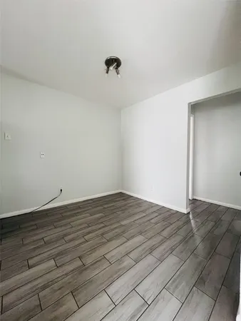 a view of an empty room with wooden floor and a ceiling fan