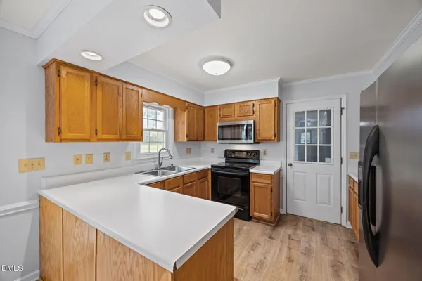 a kitchen with granite countertop a sink cabinets stainless steel appliances and a window