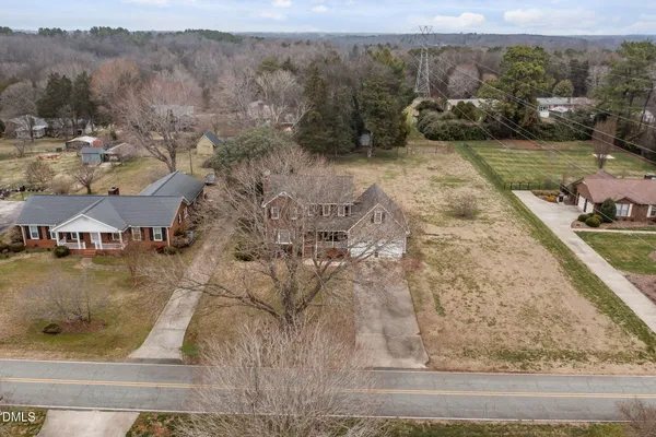 a view of a dry yard with trees and mountains in the background