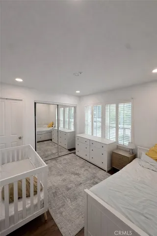 a spacious bedroom with a bed and wooden floor