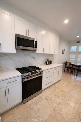 a kitchen with stainless steel appliances granite countertop a stove a sink and a microwave