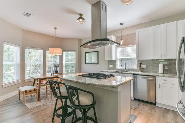 a kitchen with a stove a sink and white cabinets with wooden floor