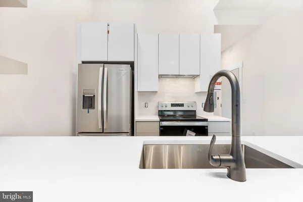 a kitchen with stainless steel appliances a stove a refrigerator a sink a counter space and cabinets