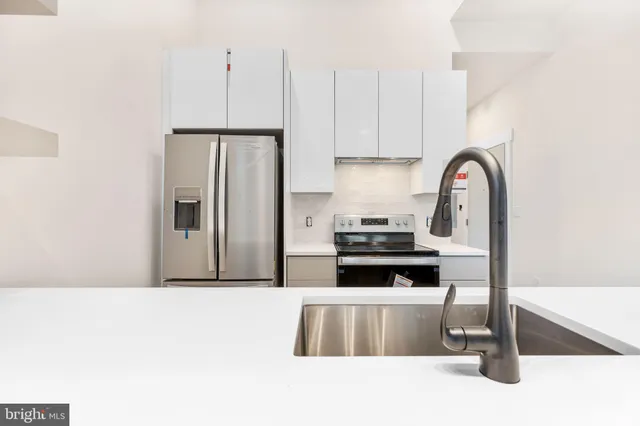 a kitchen with stainless steel appliances a stove a refrigerator a sink a counter space and cabinets