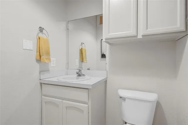 a bathroom with a granite countertop sink a mirror and a toilet