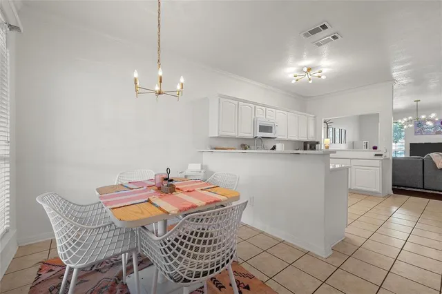 a kitchen that has a dining table chairs and white cabinets