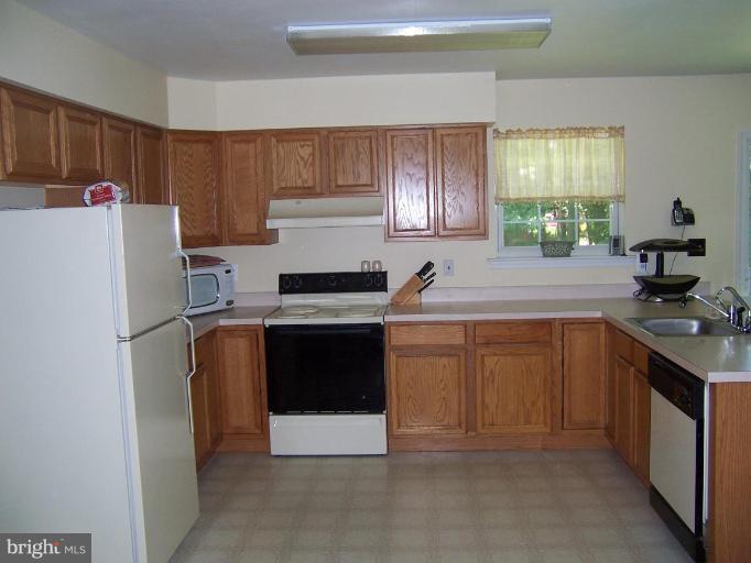 11559 San Rafael Road Lusby, MD 20657 - Photo 4 of 10 a kitchen with a refrigerator sink and cabinets
