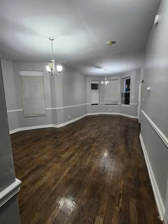 an empty room with wooden floor and chandelier