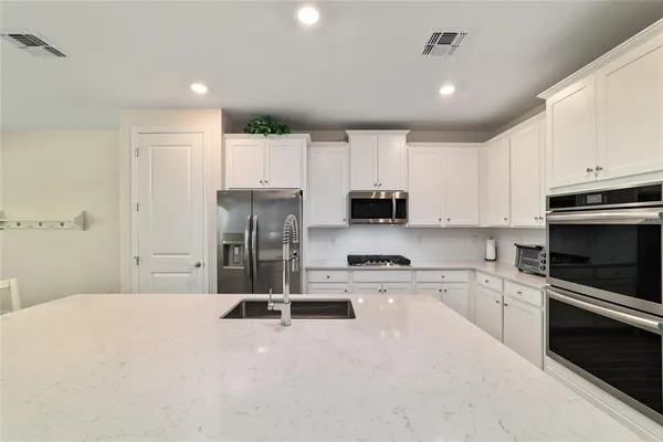 a kitchen with a refrigerator a stove top oven a sink and cabinets