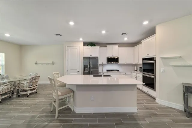 a large kitchen with kitchen island white cabinets and stainless steel appliances
