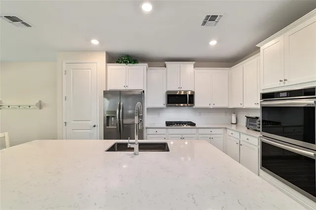 a kitchen with a refrigerator a stove top oven a sink and cabinets