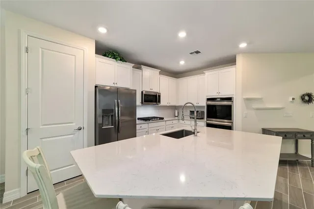 a large kitchen with stainless steel appliances a refrigerator and a stove top oven
