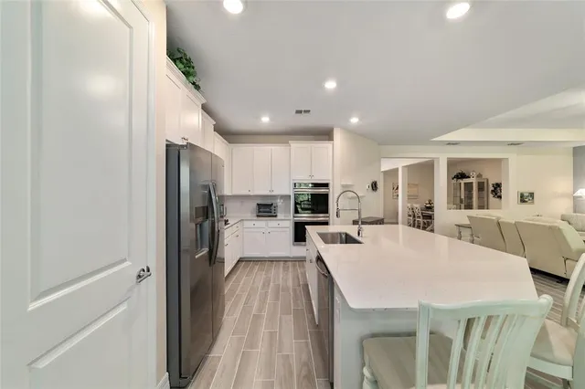 a view of a kitchen with kitchen island a refrigerator a stove a sink a dining table and chairs