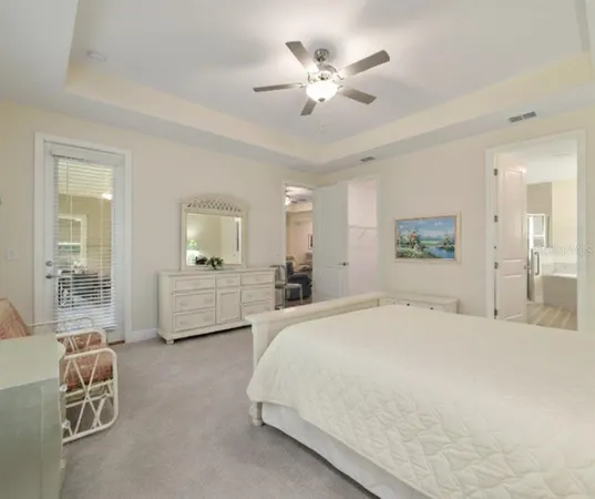 a spacious bedroom with a bed a chandelier and mirror