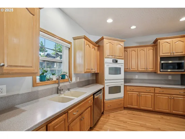 a kitchen with stainless steel appliances a sink cabinets and wooden floor