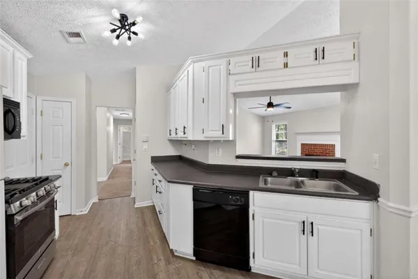 a kitchen with granite countertop a stove a sink dishwasher and a microwave oven with white cabinets
