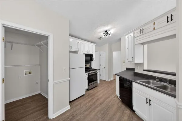 a kitchen with granite countertop a stove a sink a refrigerator and cabinets