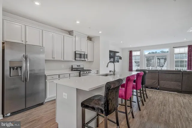 a kitchen with stainless steel appliances a dining table chairs refrigerator and sink