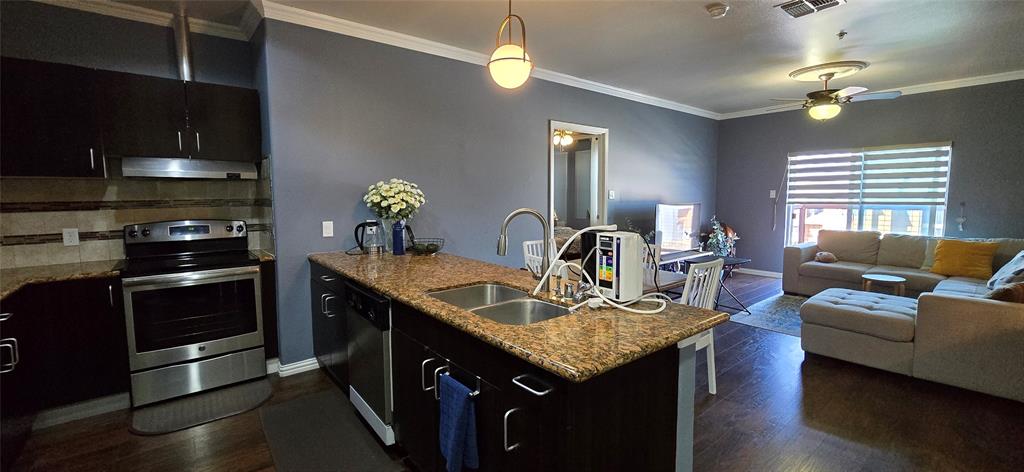 1100 West Trinity Mills Road, Unit 2045 Carrollton, TX 75006 - Photo 19 of 20 Kitchen featuring a peninsula, stainless steel appliances, open floor plan, dark wood finished floors, and light stone countertops