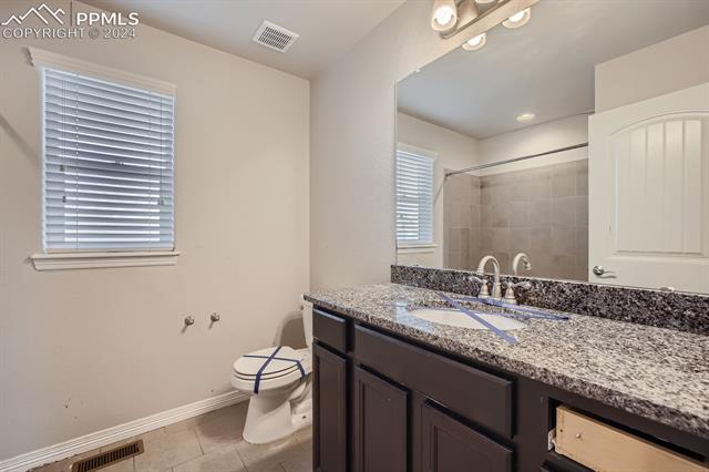 6126 Jorie Road Colorado Springs, CO 80927 - Photo 16 of 28 Bathroom featuring vanity, toilet, tile patterned floors, and tiled shower