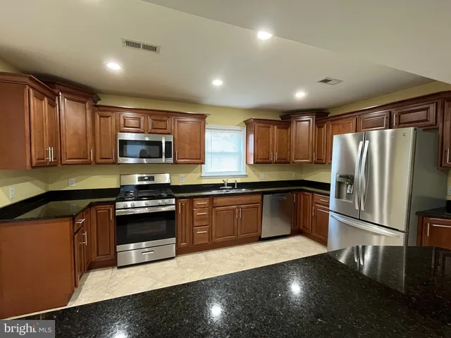 a kitchen with granite countertop a refrigerator stove and sink