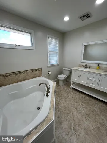 a spacious bathroom with a tub sink and mirror